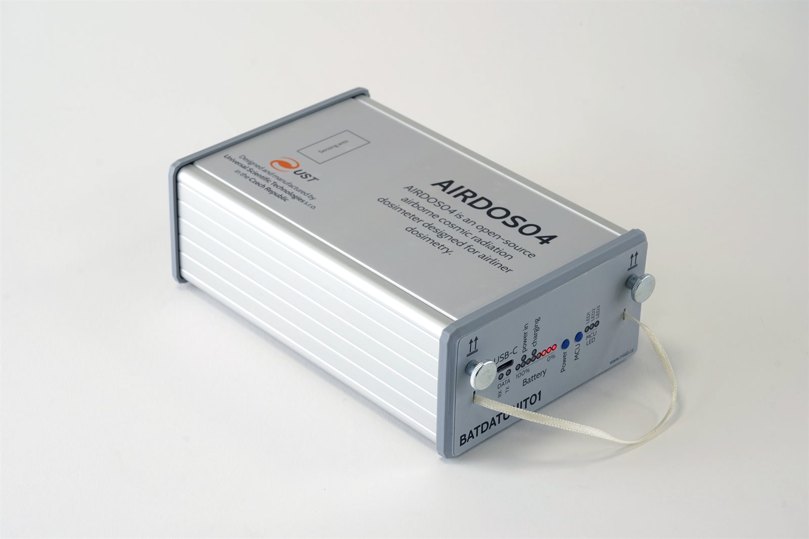 AIRDOS04, an open-source airborne cosmic radiation dosimeter in an aluminium case. The removable drawer with a USB-C port, a battery indicator and a ribbon pull is on the front.